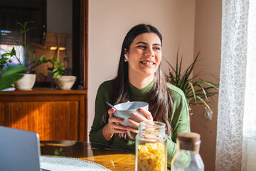 A young woman eating corn flakes for breakfast in the morning in her apartment	