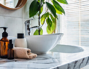 Fototapeta premium Toiletries and empty space on a white marble tabletop in a modern bright and clean bathroom.