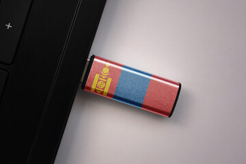 usb flash drive in notebook computer with the national flag of mongolia on gray background.
