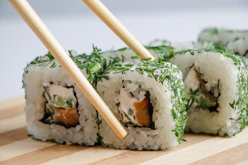 Uramaki sushi roll on wooden tray on white background.