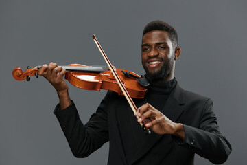 Soulful African American Man in Black Suit Playing Violin Against Gray Background with Emotion