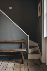 Wooden bench against grey wall and staircase. Scandinavian, rustic farmhouse interior design of modern entryway