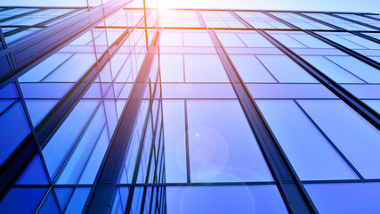 Modern office building with glass facade. Transparent glass wall of office building. Reflection of the blue sky on the facade of the building.