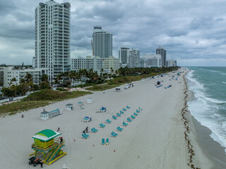 Fototapeta premium Aerial view of South Beach hotels and high rise apartment complexes prime real estate properties in Miami near the ocean with cloudy sky