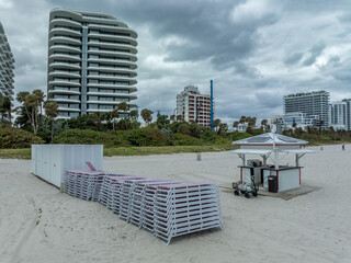 Stacked up Beach chairs on the sand of Miami South Beach with cloudy sky