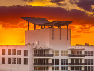 Fototapeta premium Rooftop steel pergola shade structure with orange, yellow, red sunset sky in Miami 
