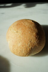 Loaf of Rustic Sourdough Bread on a White Marble Background