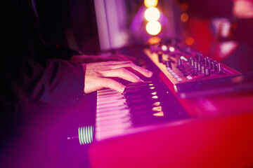 A musician plays modern piano keyboards during a concert performance.