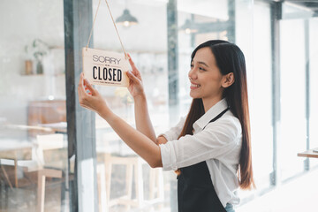 A cafe owner displays a 'Sorry We Are Closed' sign with a content smile, marking the end of a...