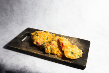 Top view of Bakwan Jagung or Dadar Jagung or Dadar Jagung . Indonesian snack made from corn and flour. Served on a wooden plate. 