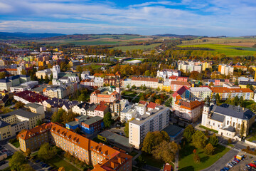 Fototapeta na wymiar Panoramic aerial view of autumn landscape of Czech town of Krnov with white building of St. Martin church and Town hall on main square on sunny day, Moravian-Silesian Region..