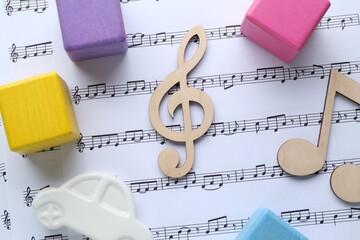 Wooden notes and toys on music sheet, flat lay. Baby song concept