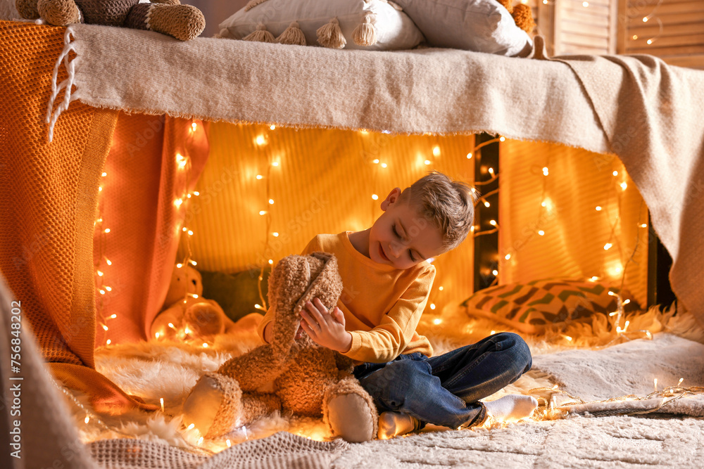 Sticker Boy playing with toy bunny in play tent at home