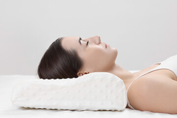 Obraz na płótnie Canvas Woman sleeping on orthopedic pillow against light grey background