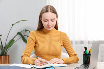 Woman taking notes at table in office
