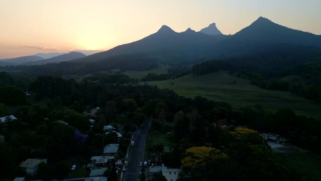 Sun setting behind mountain peaks in front of small town