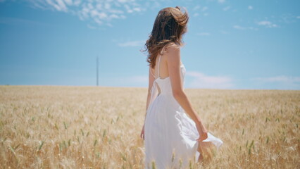 Beaming lady walking sunny wheat farmland. Happy girl spinning summer nature