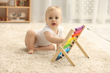 Children toys. Cute little boy playing with wooden abacus on rug at home