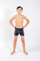 Fototapeta na wymiar Preteen male fitness model standing shirtless with hands on hips looking upward