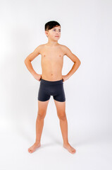 Fototapeta na wymiar Preteen male fitness model standing shirtless with hands on hips looking to his left