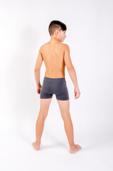 Fototapeta premium Preteen male fitness model standing shirtless with arms at his side, back turned to camera