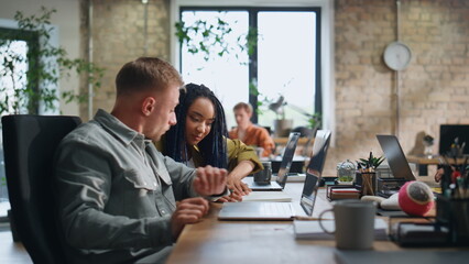 Woman asking advice colleague man sitting workspace. Multiracial team working 