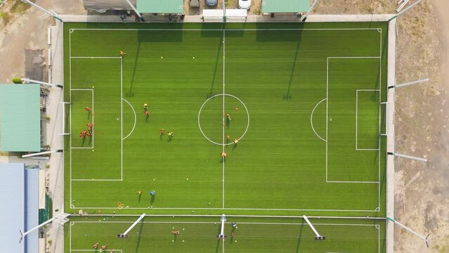 Drone footage aerial view of many people are practicing sports on the artificial grass football field, outdoor field