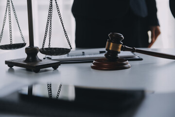 Justice and Law concept. Legal counsel presents to the client a signed contract with gavel and legal law or legal having team meeting at law firm in background