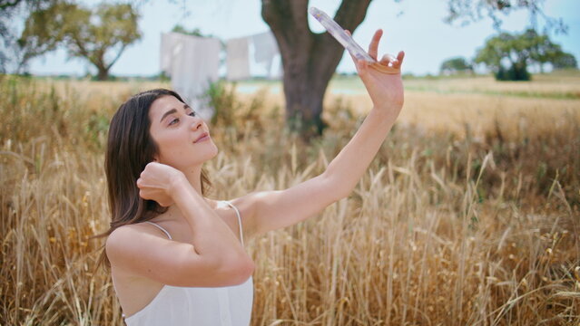 Cheerful girl posing phone camera on rural nature closeup. Woman making selfie