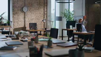 Office worker riding chair between tables in empty office. Lady having fun alone