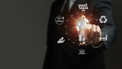 A man is pointing to a light bulb with a green and white logo on it