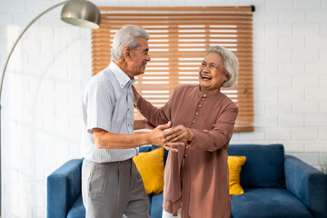 Asian active senior couple enjoy dance together in living room at home. 