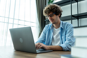 Caucasian young businessman typing on computer while working from home. 