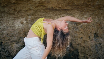 Flexible girl practicing contemporary choreography in front sandy rock close up - obrazy, fototapety, plakaty