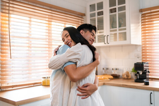 Asian young man and woman hugging each other in living room at home. 