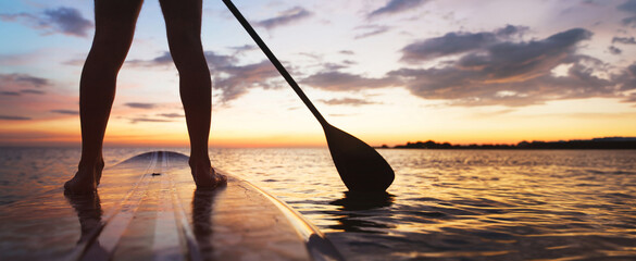 SUP, paddle board on the beach, close up of standing  legs and paddle, banner background