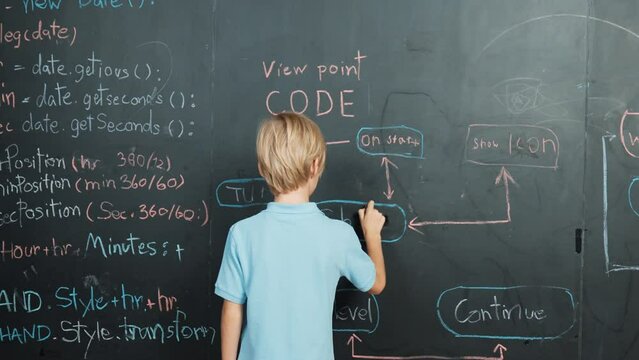 Back view of student writing engineering prompt on blackboard. Handsome clever child or boy planing a project by using coding and programing system in STEM technology classroom. Closeup. Erudition.