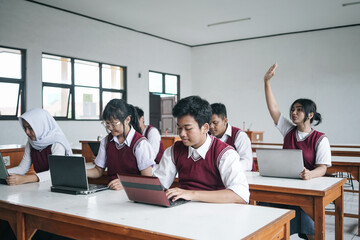 Female student raising hand in class for an answer