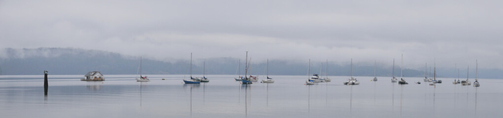 Panorama of boats in front of the shore of Cowichan Bay during a winter season on Vancouver Island in British Columbia, Canada