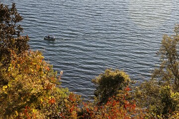Landscape of a lake in autumn and a boat with two people. 
