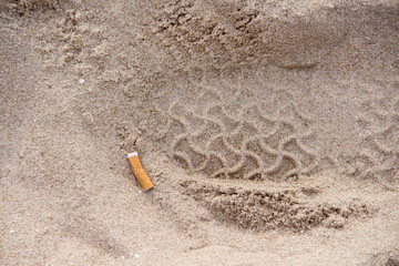 Cigarettes used on the sand beach top view garbage background