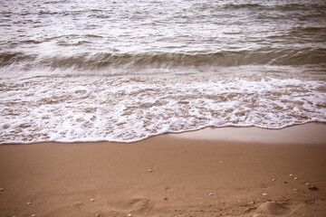 Wave water on brown sand beach in the evening background