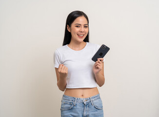Attractive Pretty young asian woman using cellphone standing on isolated white background. Happy Excited Beautiful young asian shopping online payment with mobile phone. Playing game on smartphone
