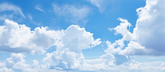 The sky is painted with electric blue hues, adorned with fluffy white cumulus clouds. A natural...