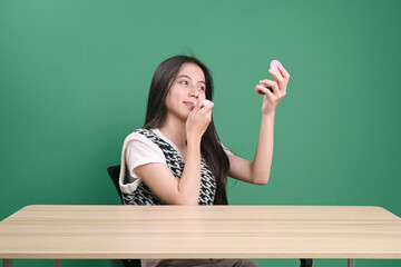 Female Teenager Using Lipstick Isolated Green Background 