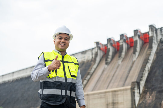 Professional asian maintenance engineer man with safety helmet in construction site dam with hydroelectric power plant and irrigation. Manager engineer man working at project big building.