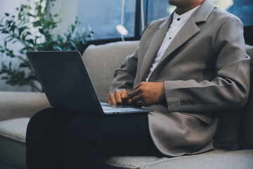 Young businessman working in office, sitting at desk, looking at laptop computer screen