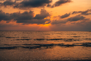 Sunset at sea with orange sky and waves