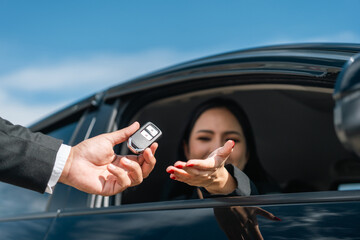 Young asian businesswoman buying new car with sale manager. she getting key and go to driving car very happy and proud. Buy sell rent concept. Hand sending key vehicle contract business car deal