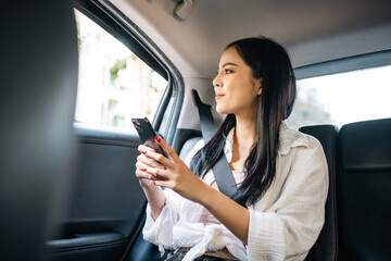 Asian Woman Traveler sitting in car back seats using smartphone call taxi service in application....